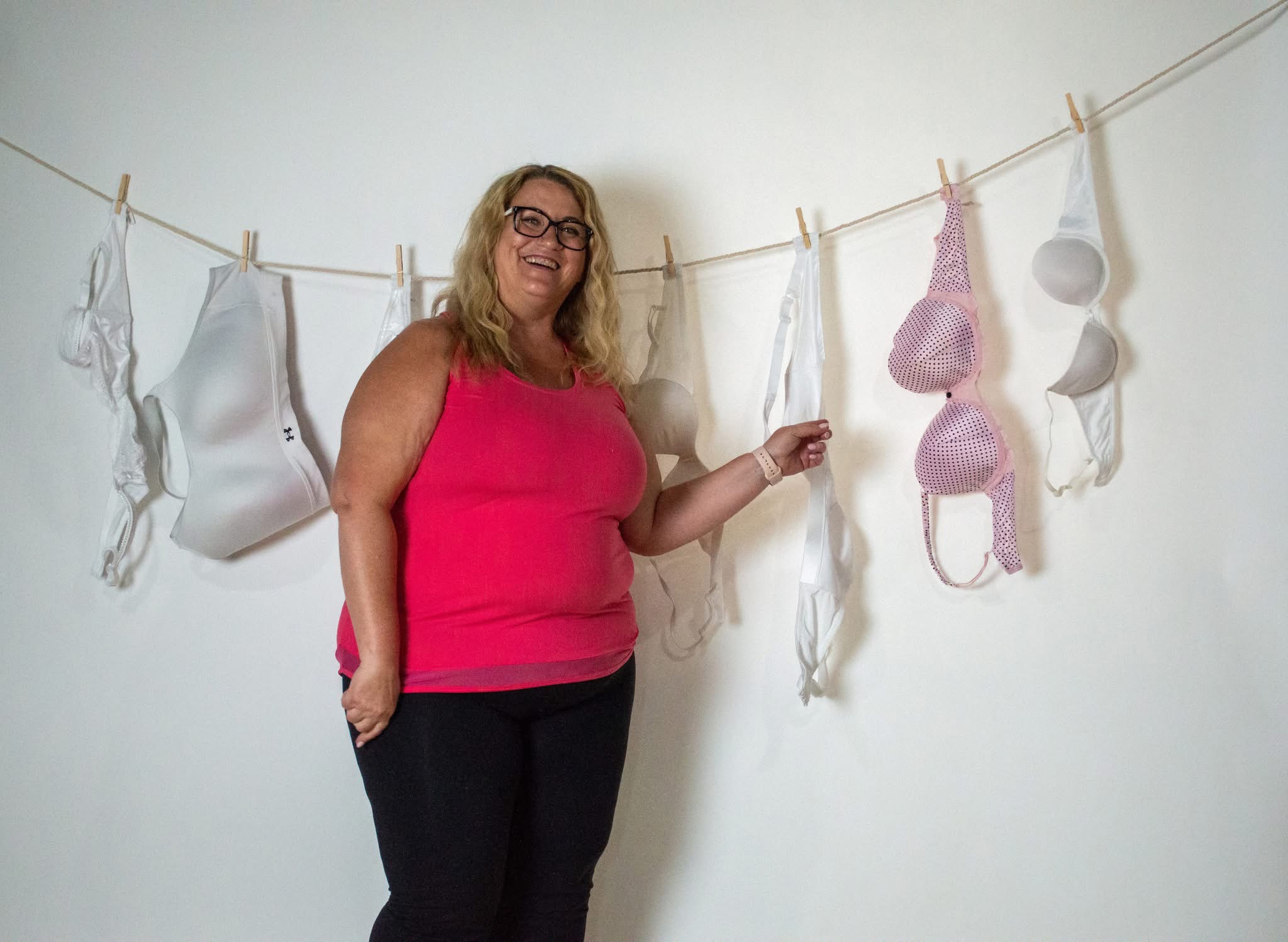Woman laughing beside a clothesline of bras at a breast cancer awareness gathering