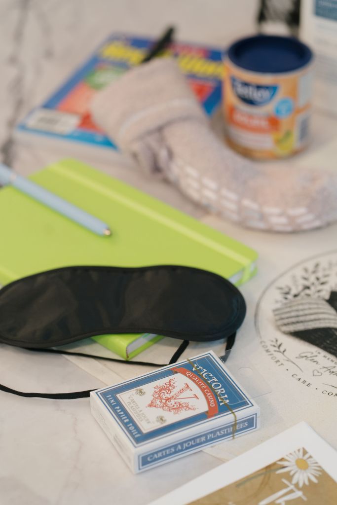 Comfort basket contents spread out including the branded tote bag, a sleep mask, playing cards, Tetley tea, Lubriderm lotion, warm socks, and a thank-you card
