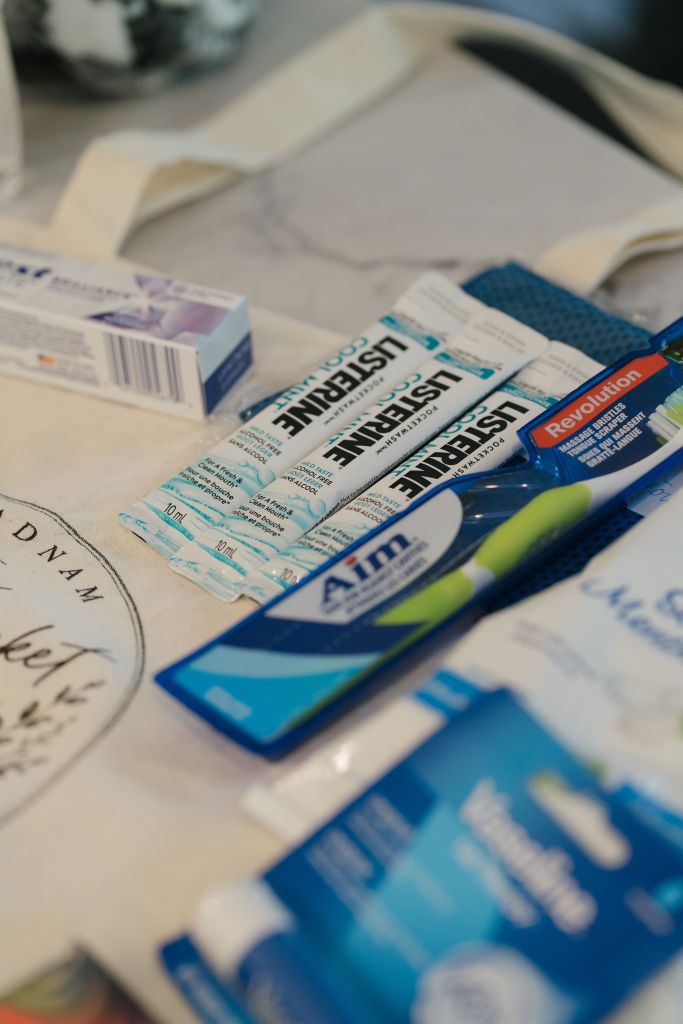 Listerine mouthwash packets, Aim toothpaste, and a toothbrush laid on the branded tote β oral care items for treatment days