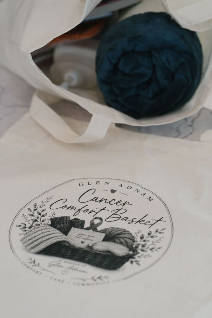 Sleep mask, journal with pen, and a deck of playing cards from the comfort basket, with basket logo visible in the background